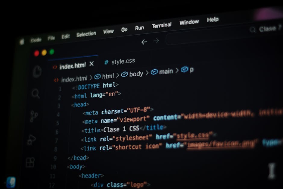 A close-up photograph of a computer screen displaying lines of HTML code with multicolored syntax highlighting, including tags and attributes in pink, yellow, and green. The code features elements suc